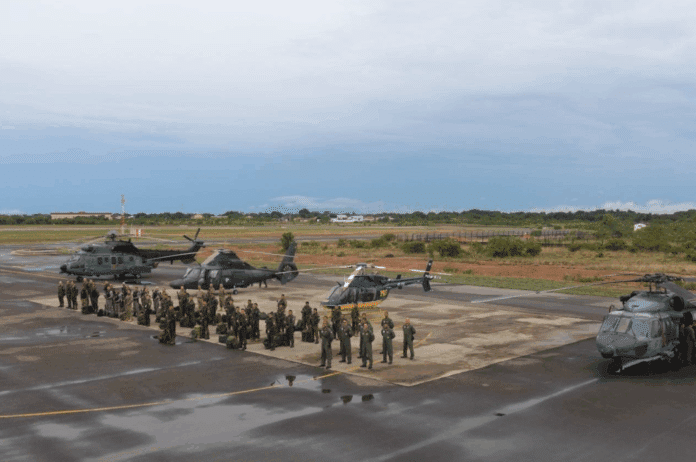 Helicópteros e soldados em base aérea militar.